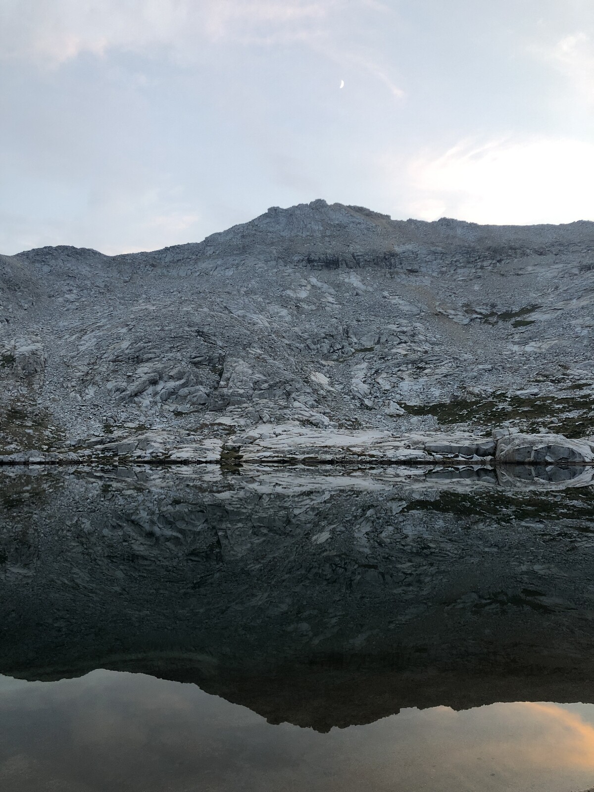 Mirror-still alpine lake reflecting peak and rocky shores