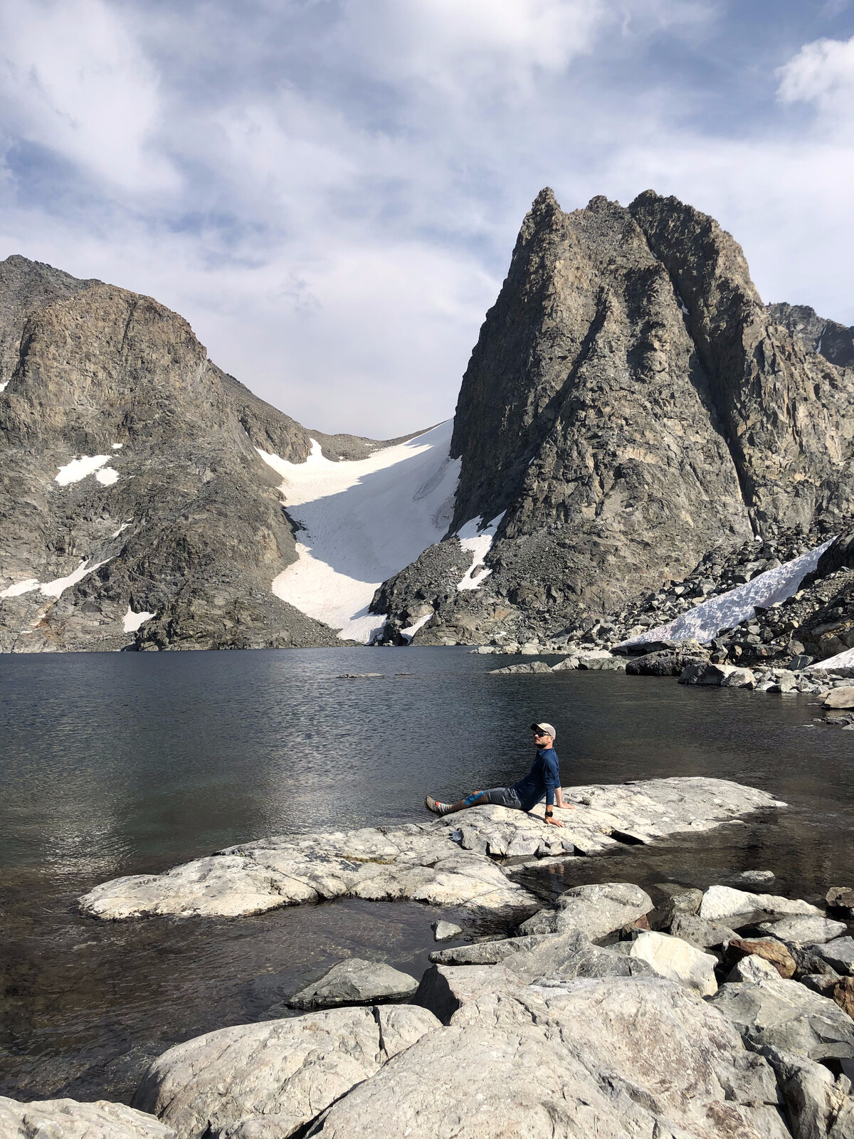 Hiker beside alpine lake with dramatic jagged peak reflection